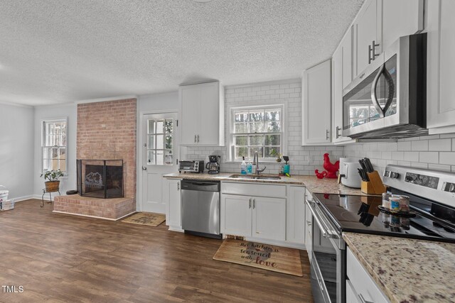 kitchen with white cabinetry, sink, light stone counters, and stainless steel appliances