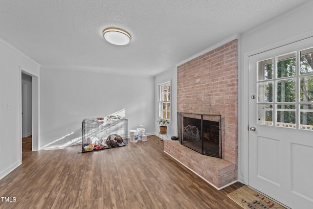 unfurnished living room with dark hardwood / wood-style floors, a textured ceiling, a brick fireplace, and a wealth of natural light