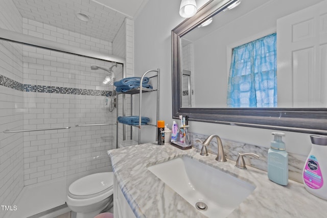 bathroom with crown molding, tiled shower, vanity, and toilet