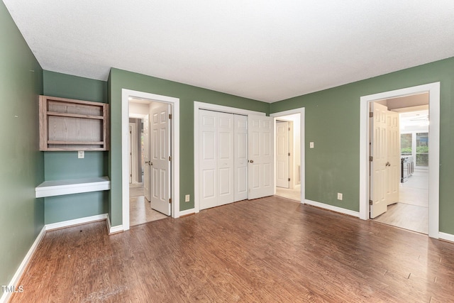 unfurnished bedroom featuring ensuite bathroom and hardwood / wood-style floors