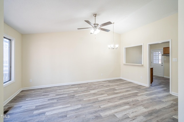 empty room featuring ceiling fan with notable chandelier, vaulted ceiling, and light hardwood / wood-style flooring