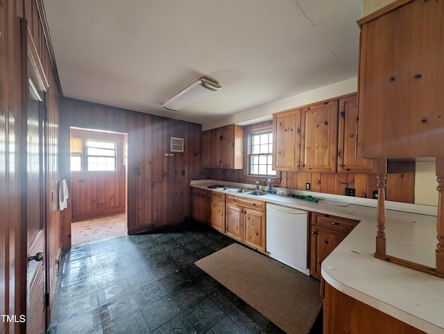 kitchen featuring dishwasher, sink, a wall unit AC, and wood walls