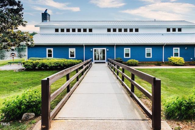 view of front of house featuring a water view, french doors, and a front lawn