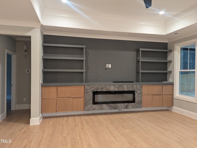 unfurnished living room with light hardwood / wood-style floors, a premium fireplace, built in features, and ornamental molding