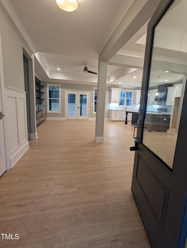 interior space featuring light hardwood / wood-style floors, a tray ceiling, and crown molding