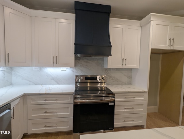 kitchen featuring white cabinetry, appliances with stainless steel finishes, light stone counters, and premium range hood