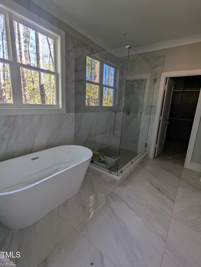 bathroom with ornamental molding and shower with separate bathtub