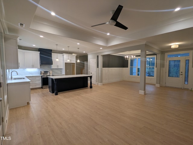 living room featuring ceiling fan with notable chandelier, light hardwood / wood-style floors, sink, and crown molding