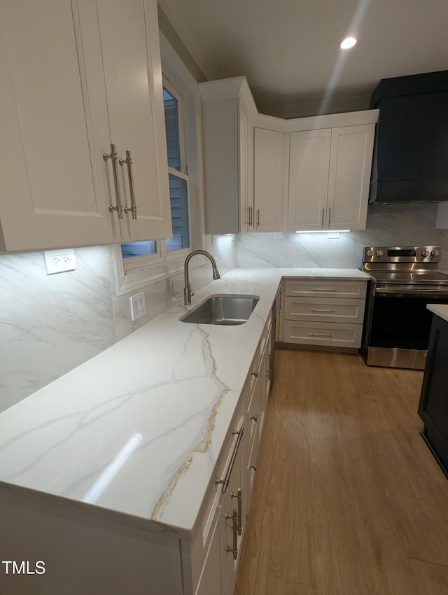 kitchen featuring sink, stainless steel electric range oven, white cabinetry, and light stone countertops