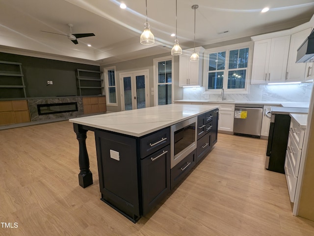 kitchen with white cabinetry, stainless steel appliances, a center island, a tray ceiling, and pendant lighting