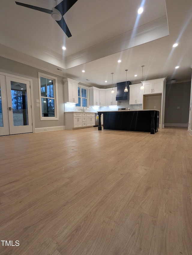 kitchen with white cabinets, a raised ceiling, a spacious island, and decorative light fixtures