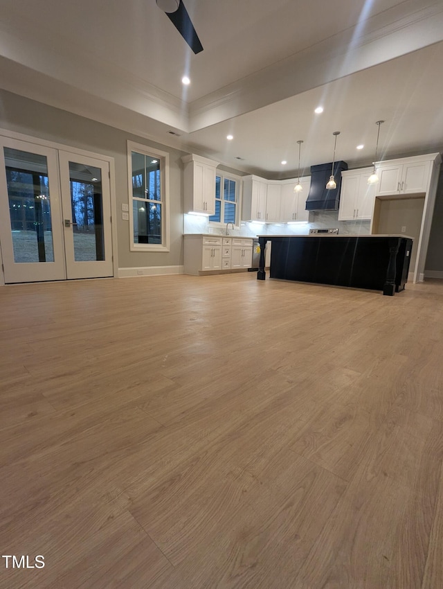 interior space with white cabinets, hanging light fixtures, light hardwood / wood-style flooring, and a large island