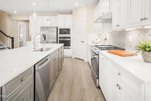 kitchen featuring sink, hanging light fixtures, appliances with stainless steel finishes, light hardwood / wood-style floors, and white cabinetry