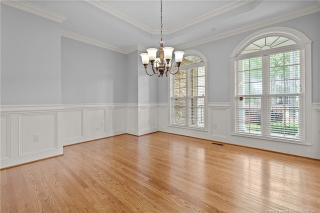 unfurnished dining area featuring a notable chandelier, a raised ceiling, crown molding, and light hardwood / wood-style flooring