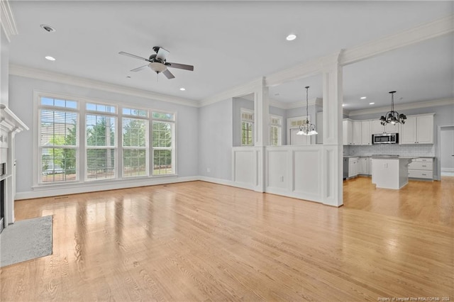 unfurnished living room featuring crown molding, light hardwood / wood-style flooring, and ceiling fan with notable chandelier