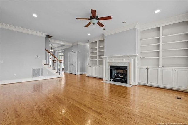 unfurnished living room with built in shelves, light hardwood / wood-style flooring, ceiling fan, and ornamental molding