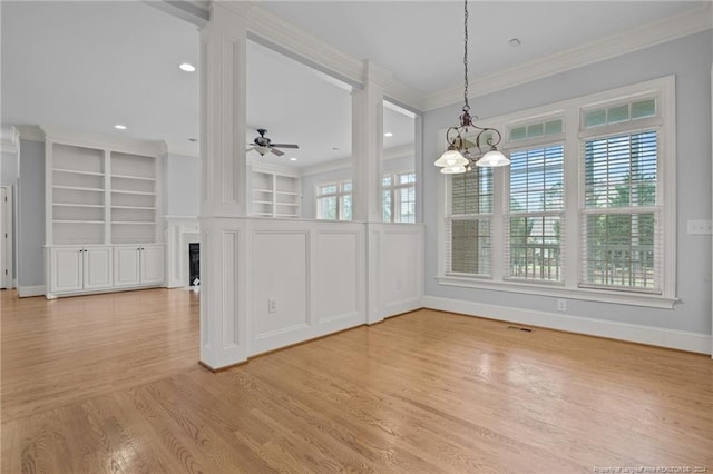 unfurnished dining area featuring crown molding, ceiling fan with notable chandelier, and light wood-type flooring