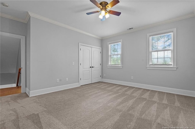 unfurnished bedroom with ceiling fan, crown molding, and light carpet