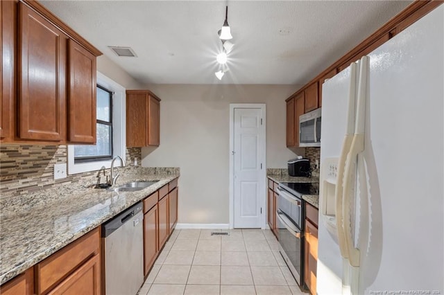 kitchen featuring sink, light stone countertops, tasteful backsplash, light tile patterned flooring, and stainless steel appliances