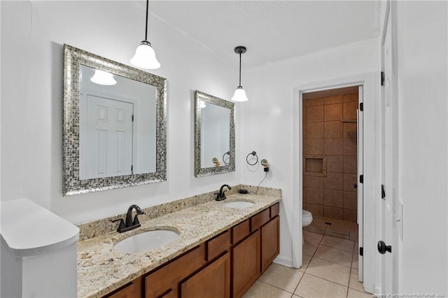 bathroom featuring tile patterned flooring, vanity, toilet, and tiled shower