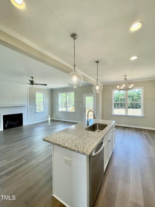 kitchen featuring stainless steel dishwasher, sink, hanging light fixtures, and an island with sink