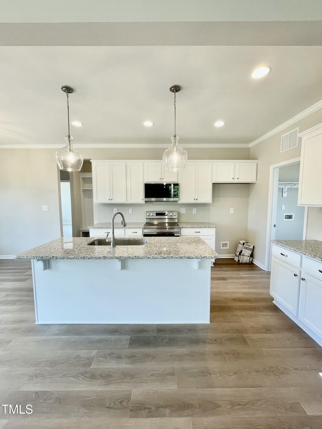 kitchen featuring appliances with stainless steel finishes, decorative light fixtures, a kitchen island with sink, and sink