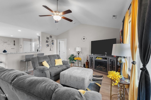 living room with a fireplace, ceiling fan, light hardwood / wood-style flooring, and vaulted ceiling