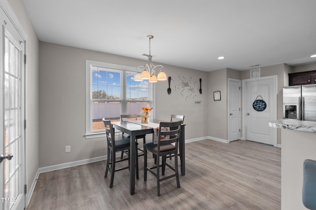 dining space featuring light hardwood / wood-style floors and a notable chandelier