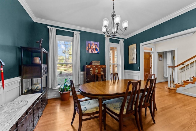 dining area featuring ornamental molding, light hardwood / wood-style floors, and a notable chandelier