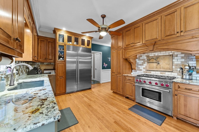 kitchen with sink, high end appliances, light stone counters, and backsplash