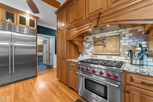 kitchen featuring ornamental molding, backsplash, light stone countertops, and high quality appliances