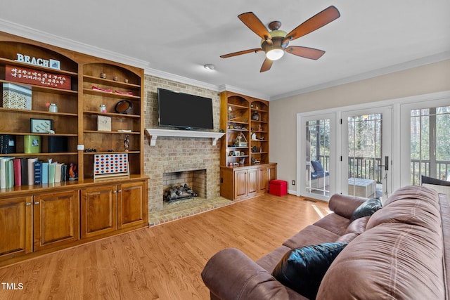 living room with a brick fireplace, ceiling fan, light hardwood / wood-style floors, and a healthy amount of sunlight