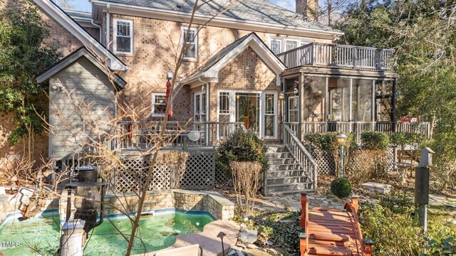 back of property featuring a jacuzzi, a balcony, and a sunroom