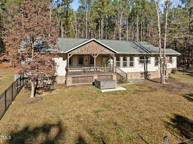 back of property featuring a yard, a hot tub, and a deck