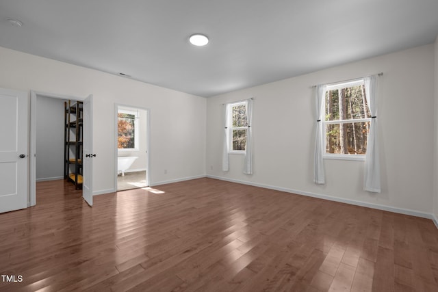 empty room with dark hardwood / wood-style floors and a wealth of natural light