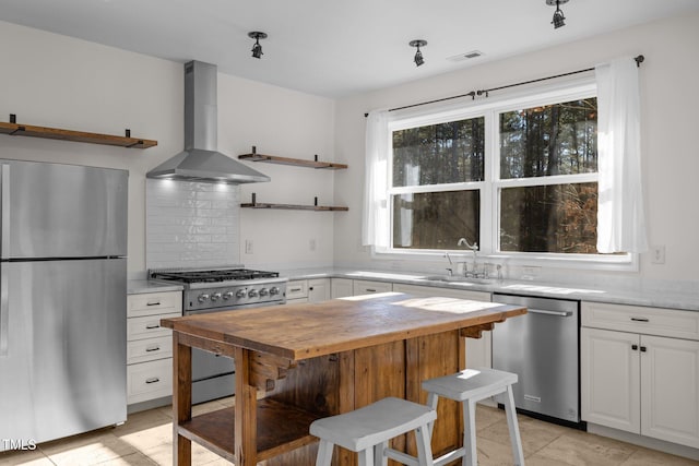 kitchen with white cabinetry, wall chimney range hood, sink, and appliances with stainless steel finishes