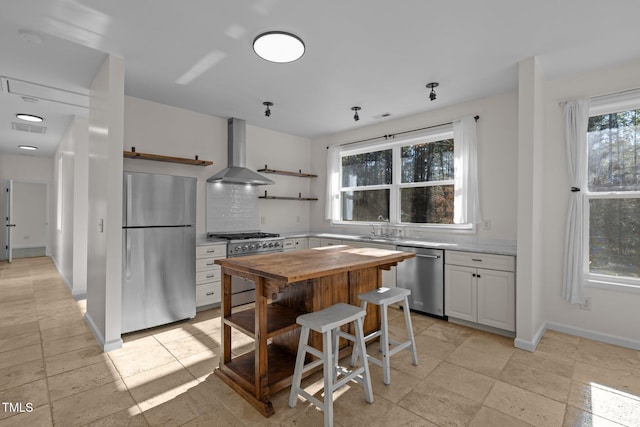 kitchen with decorative backsplash, wall chimney exhaust hood, stainless steel appliances, sink, and white cabinets