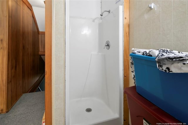 bathroom with wood walls and walk in shower