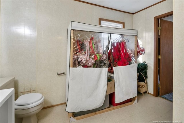bathroom with toilet, ornamental molding, and tile walls