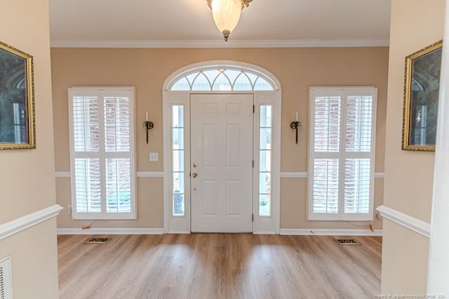 entrance foyer with light wood-type flooring, crown molding, and a healthy amount of sunlight