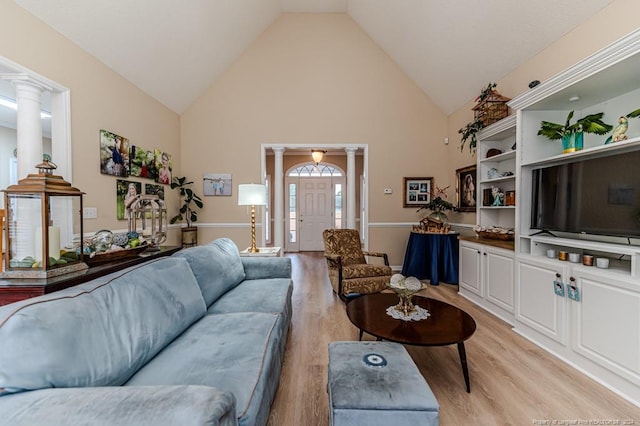 living room featuring decorative columns, high vaulted ceiling, and light hardwood / wood-style flooring