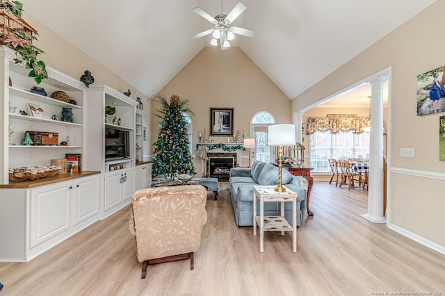 living room with ceiling fan, light wood-type flooring, high vaulted ceiling, and decorative columns