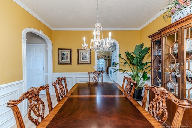 dining room with a textured ceiling, crown molding, a notable chandelier, and hardwood / wood-style flooring