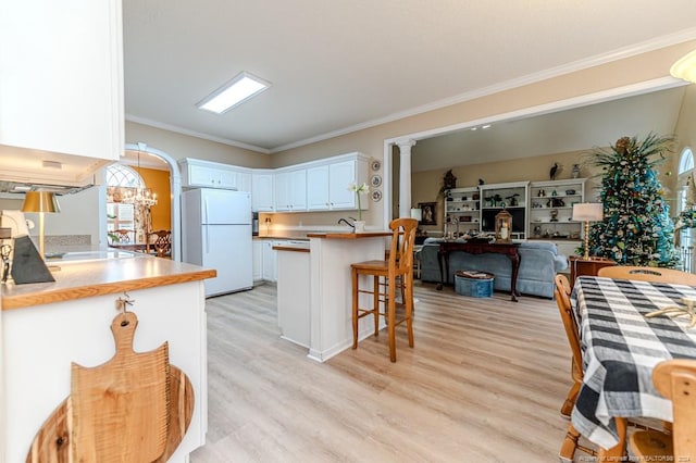 kitchen with white cabinets, a kitchen breakfast bar, white refrigerator, a notable chandelier, and kitchen peninsula