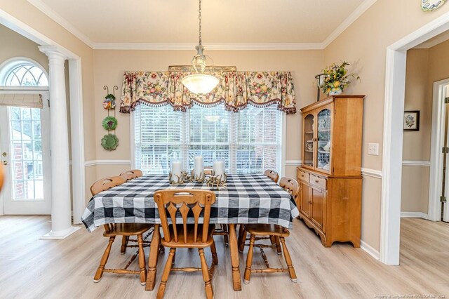 dining space with crown molding, light hardwood / wood-style flooring, and decorative columns