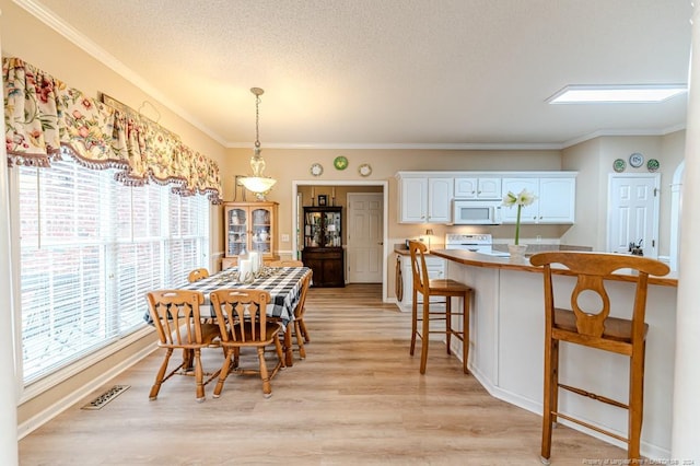 dining room with crown molding, light hardwood / wood-style floors, and a textured ceiling