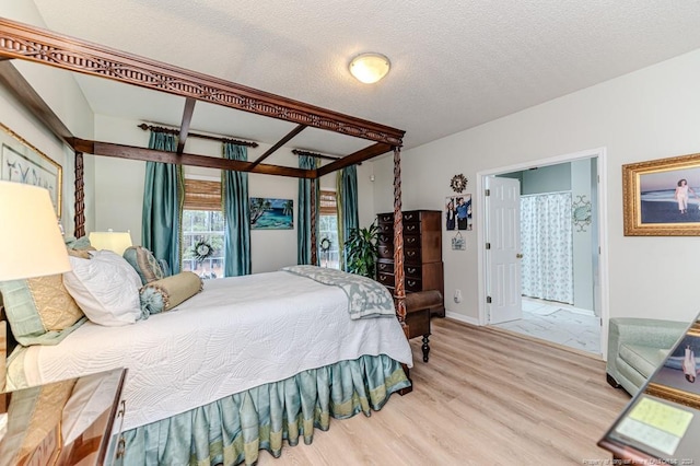 bedroom featuring connected bathroom, light hardwood / wood-style flooring, and a textured ceiling