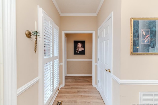 corridor with light hardwood / wood-style floors and ornamental molding