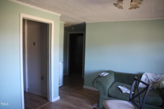 living area with ornamental molding, a textured ceiling, and hardwood / wood-style flooring