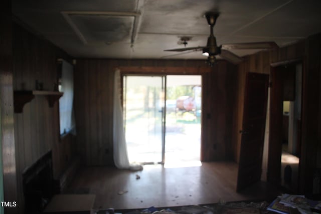 living room featuring ceiling fan and wood walls